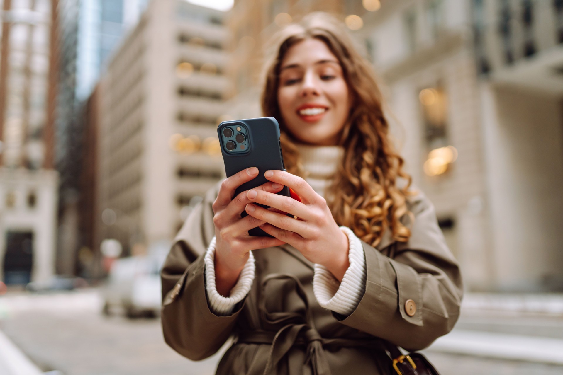 Portrait of happy woman with smartphone in the street city.